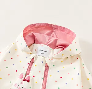 Detailed view of polka dot kids windbreaker featuring hood and soft pink lining