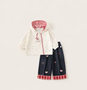 Detail of white hooded jacket with polka dots and embroidery on blue denim trousers