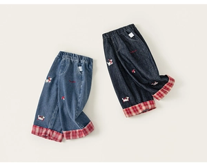 Dettaglio dei pantaloni in denim per bambini con ricamo a cane e risvolto a quadretti