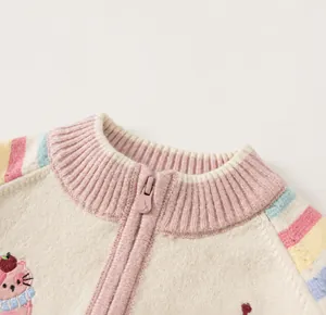 Detail van gestreept gebreid vest voor meisjes met regenboogkraag en kattenborduurwerk