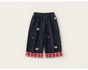 Dettagli dei pantaloni in denim per bambini con ricami e risvolti a quadri rossi