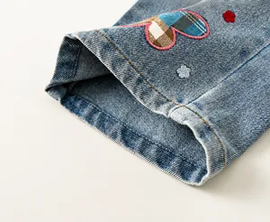 Detail van lichtblauwe denim manchetten met ingewikkelde hart- en bloemborduursels