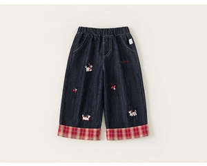 Detail of girls denim wide-leg pants featuring cute cartoon embroidery and plaid hem