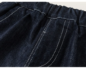 Dettaglio dell'elastico in vita su pantaloni di jeans blu scuro con cuciture bianche