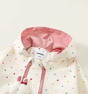 Detailed close-up of hooded windbreaker with colorful polka dots and pink lining