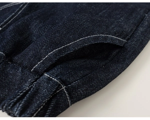 Dettaglio del tessuto denim indaco scuro con cuciture bianche a contrasto e rifiniture