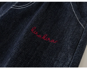 Macro di tessuto denim blu scuro con ricamo rosso kurakura e cuciture a contrasto