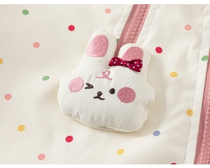Detail of baby hooded jacket featuring a 3D bunny patch and vibrant colorful polka dots
