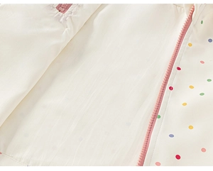 Detail of pink resin zipper and colorful polka dot pattern on white windbreaker fabric