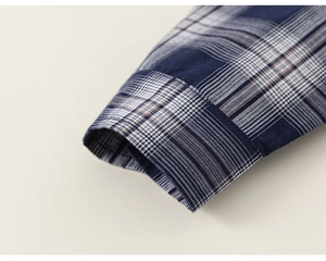 Gros plan du poignet de chemise à carreaux bleu et marron avec coutures soignées