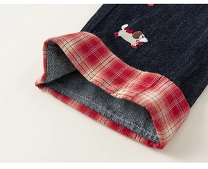 Dettaglio di jeans per bambini con risvolto a quadretti rossi e ricamo di cucciolo