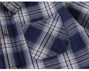 Détail d'une chemise à carreaux bleu marine avec col classique et poche avant à boutons bruns