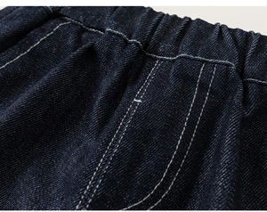 Close-up of durable dark blue denim fabric with elastic waistband and precise white stitching