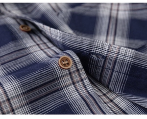 Vue détaillée du tissu d'une chemise à carreaux bleu et blanc avec bouton marron