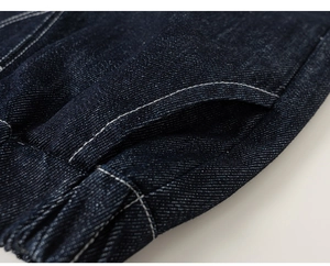 Detail of dark blue denim jacket featuring elastic waist and white contrast stitching