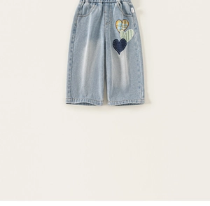 Detail of light blue girls jeans featuring triple heart embroidery on the leg side