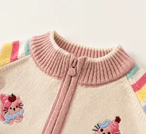 Detail van gebreid meisjesvest met regenboogstrepen op de mouwen en kattenborduur