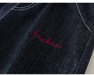 Detailed macro view of dark blue denim fabric with white stitching and red kirakira embroidery