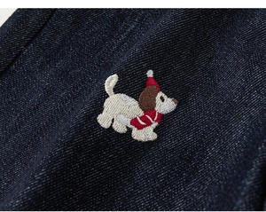 Detailed macro view of denim fabric with cute puppy embroidery and red scarf accent
