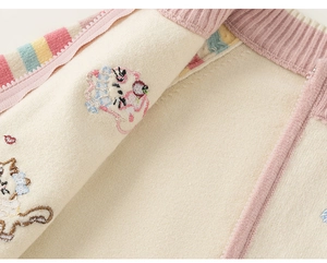 Detailopname van gebreide stof met regenboogstrepen en schattig kattenborduurwerk erop