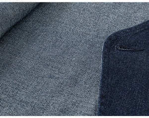 Détail du tissu denim montrant la texture sergée et la couture fine sur la boutonnière