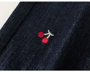 Detailed close-up of cherry embroidery on navy blue cotton twill jacket fabric