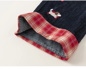 Detail of kids denim pants cuff with red checkered lining and small dog embroidery