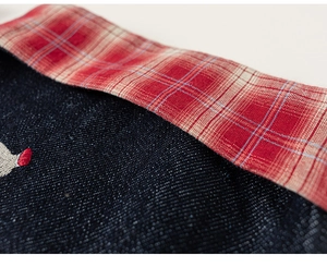 Close-up of children jacket with navy denim, red plaid fabric and cartoon embroidery