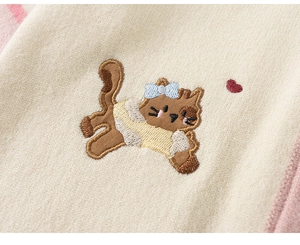 Detail van het witte gebreide vest met schattig kattenborduurwerk en roze hartaccenten