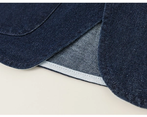Gros plan sur la texture du denim bleu et les détails de couture renforcée du vêtement