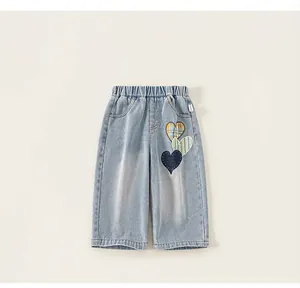 Detailed close-up of girls' light blue denim pants with cute heart patchwork embroidery
