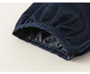Gros plan des poignets élastiques à volants sur un vêtement en denim bleu foncé