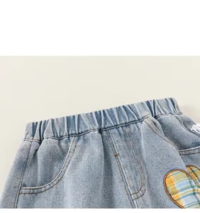 Detail of elastic waistband and heart embroidery on light blue denim jeans