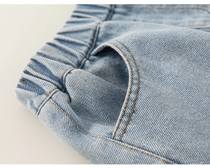 Detail of light blue girls' denim pants featuring elastic waist and reinforced stitching