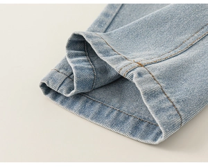 Detailed macro view of light blue denim fabric with yellow contrast stitching on the hem