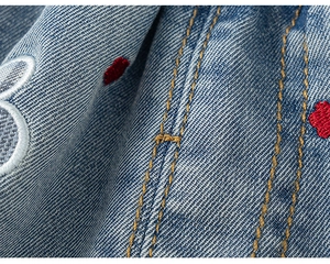 Detalle de pantalón vaquero azul para niña con costura doble amarilla y bordado
