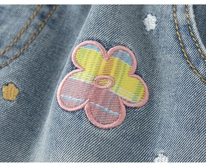 Detalle de tela vaquera con bordado de flores lindas y costuras rosas en los pantalones