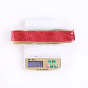 Detail of red Christmas ribbon with gold trim on electronic scale for weight measurement
