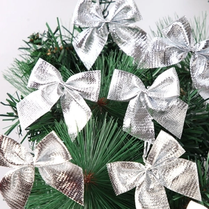 Silver metallic Christmas bow ornaments placed on green pine branches for holiday decoration