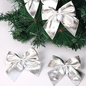 Set of shiny silver Christmas bows with glitter finish on pine branch decoration