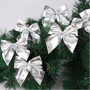Close-up of small silver metallic bows tied to green Christmas tree branches