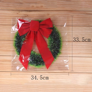 Close-up of green tinsel Christmas wreath with red bow measuring 34.5cm by 33.5cm