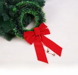 Detail of Christmas wreath with green pine needles, a red velvet bow and golden bells