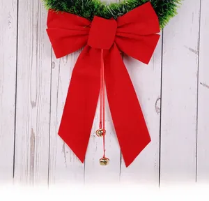 Detail of red velvet bow with golden bells on a green Christmas pine wreath