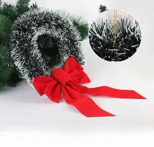 Detail of green tinsel Christmas wreath with snowy finish and large red velvet bow