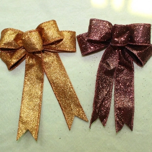 Glittery gold and deep red decorative bows with long tails for festive party settings