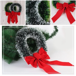 Detail showing plush Christmas tinsel wreath with large red velvet bow on wooden background