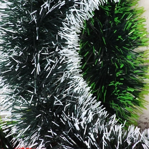 Close-up of fluffy three-color Christmas tinsel garland in dark green, light green, and white