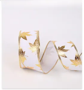 Detail of white Christmas ribbon with gold maple leaf print and metallic woven edges