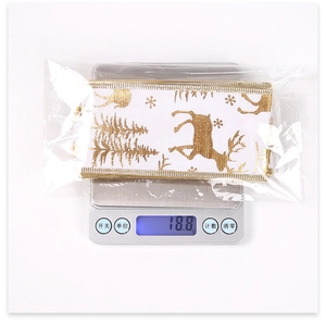 Close-up of Christmas ribbon with gold elk and tree patterns on a digital weight scale